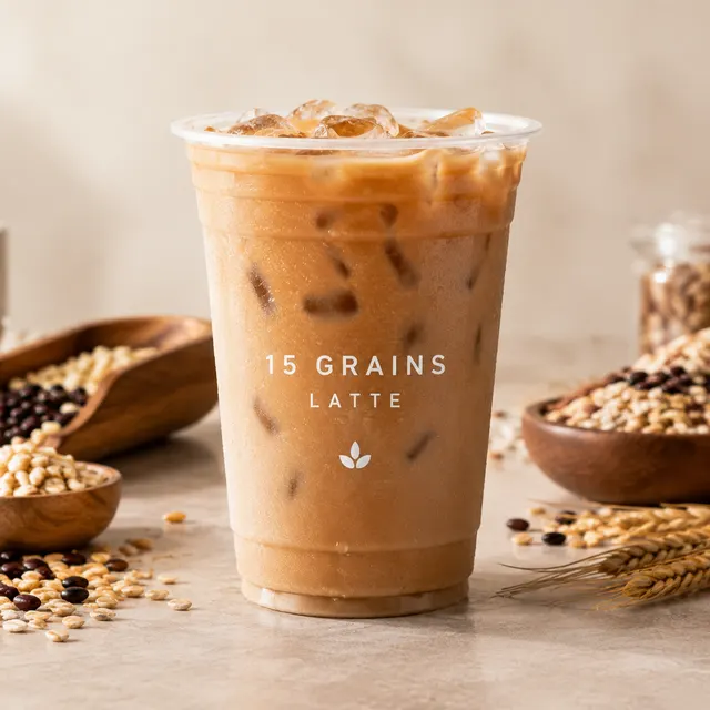 Iced 15 grains latte in a clear cup, with bowls of roasted grains around it